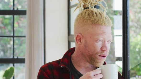 Thoughtful albino african american man with dreadlocks looking at the window