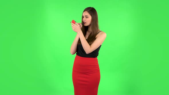 Girl Paints Her Lips Looking in Red Mirror