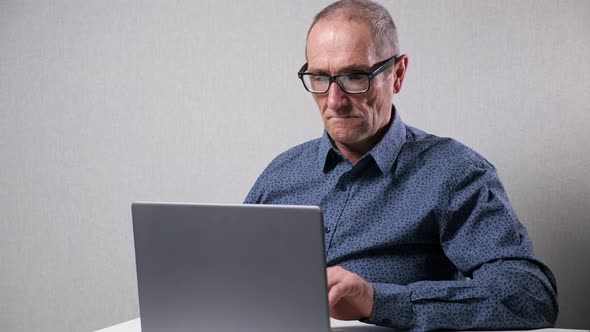 Senior Man Works in Computer Sitting at White Desk in Office