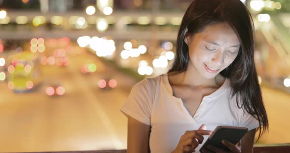 Young woman looking at mobile phone in city at night