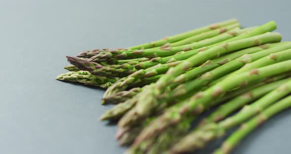 Video of close up of fresh asparagus over grey background