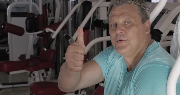 Senior Man with Thumb Up and Smile Between Exercises in Gym alt