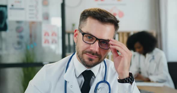 Doctor Taking off His Glasses when Looking Into Camera with Sincerely smile