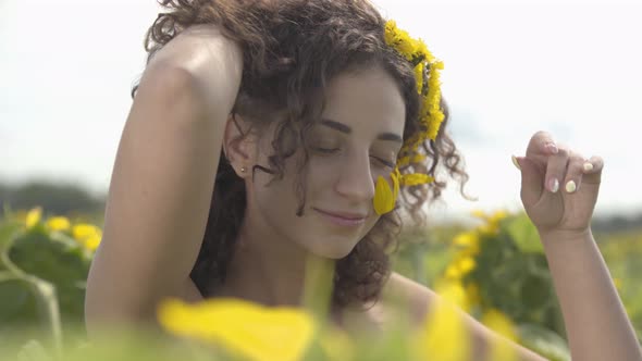 Portrait of Beautiful Curly Playful Girl Looking at the Camera Smiling Standing on the Sunflower