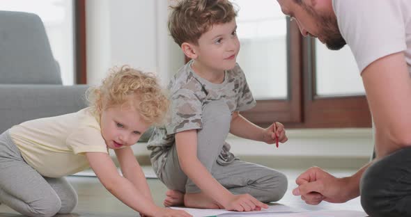 Close Up of a Little Boy and a Little Girl and Their Father are Drawing with Pencils on the White