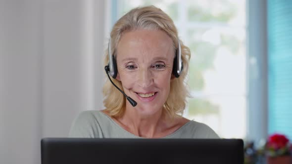 Close Up Portrait of Senior Woman in Headphones Having Video Chat on Laptop