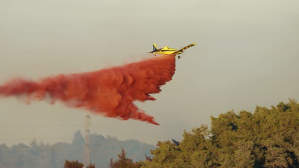 Fire fighter plane drops fire retardant on a forest fire in the hills