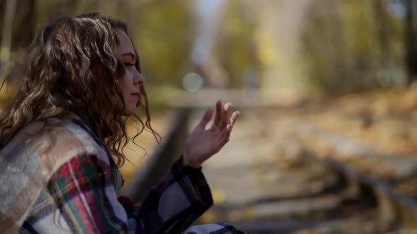 Beautiful Woman is Sitting on Old Rail of Abandoned Railway Road in Autumn Day