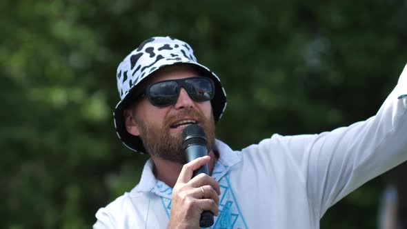 Portrait of a Stylish Bearded Man Speaking Through a Microphone Outdoors