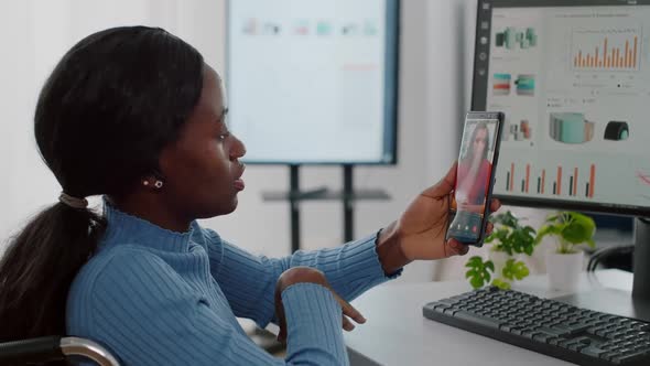 African Disabled Worker Holding Smartphone Talking with Remote Partner on Video Call