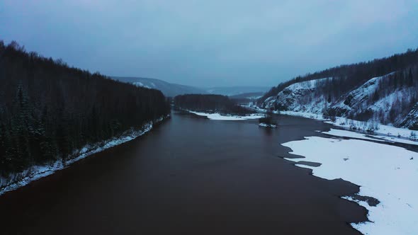 Aerial View of the River with Hills and Snow Forest on the Banks