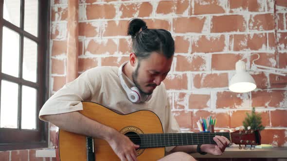 Asian man designer working home using laptop in living playing guitar and singing in living room.