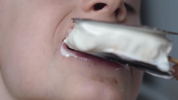 closeup caucasian boy 6 years old licks melted chocolate ice cream on a stick.ice cream saves from h