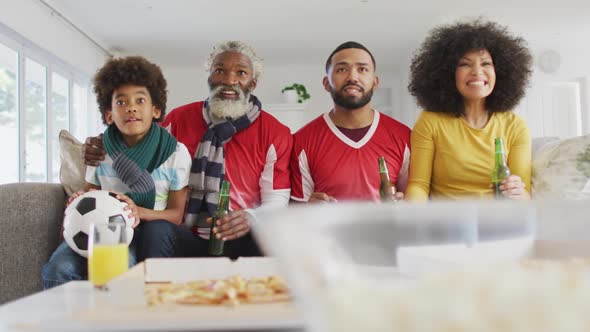 Multi-generation family cheering while watching sports on TV at home