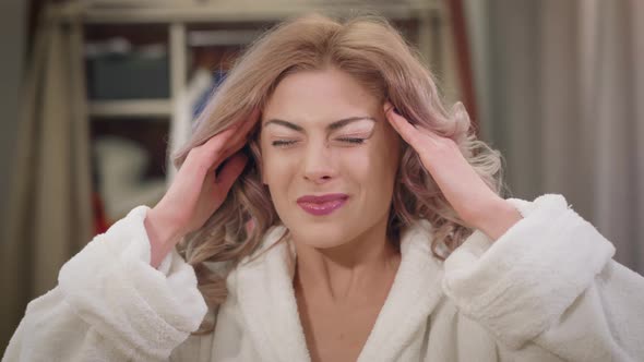 Close-up of Pretty Caucasian Woman with Severe Headache. Beautiful Girl Holding Temples with Hands