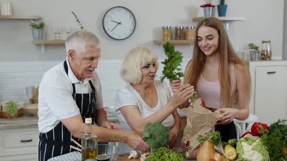 Senior Couple in Kitchen Receiving Vegetables From Granddaughter. Healthy Raw Food Nutrition