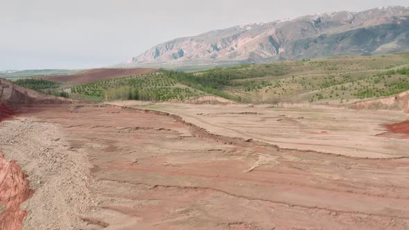 Aerial Drone Footage of Beautiful Vast Sandy Valley and Green Foothills of Mountains