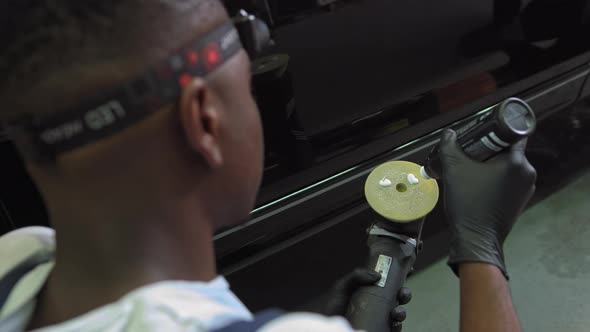 A Young AfricanAmerican Mechanic Applies Car Polishing Paste