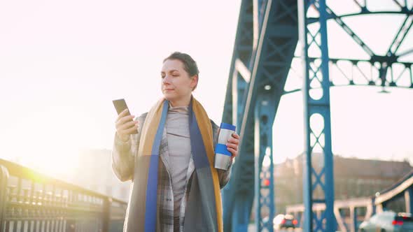 Businesswoman Walking in a Frosty Sunny Morning Drinking Coffee and Using Smartphone