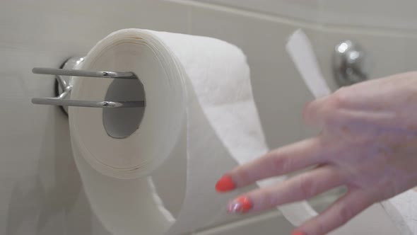 Woman Rips Off Toilet Paper That Hangs on the Wall in the Toilet