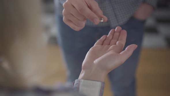 Close-up of Female Caucasian Hand Taking Wedding Ring From Unrecognizable Husband and Closing Fist