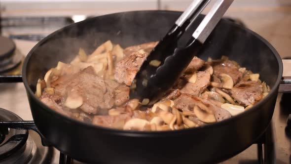 Fried Pieces of Pork with Mushrooms in a Pan, Close-up.