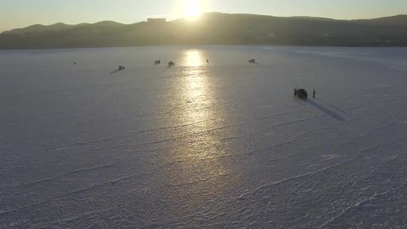 Winter Frozen Sea Captured From a Drone Fishermen Sit on Ice and Fishing