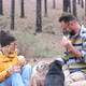couple of two happy people and two dogs eating together doing a picnic on the ground - VideoHive Item for Sale