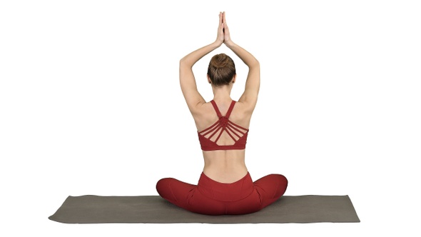 Young sporty woman sitting in lotus pose join hands above