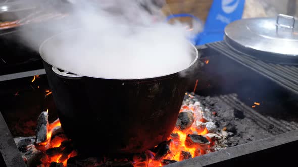 Big Vat of Hot Food Is Cooked on the Coals on a Street Christmas Market