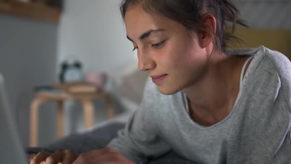 Young Woman Using Laptop in her Bedroom