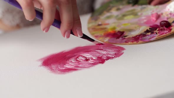 Close-up of a Girl in a Draws on a White Canvas Pink Paint with a Brush