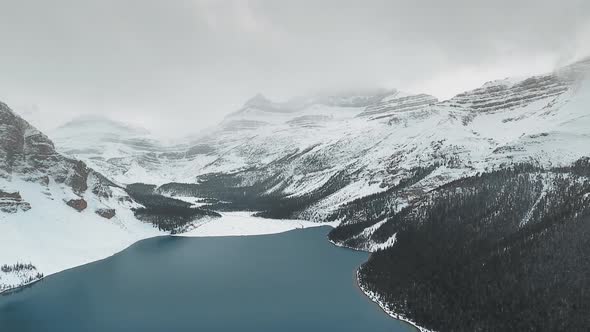 Bird's-eye aeroal shot of Bow Lake at the foot of snow-covered mountains in Alberta, Canada