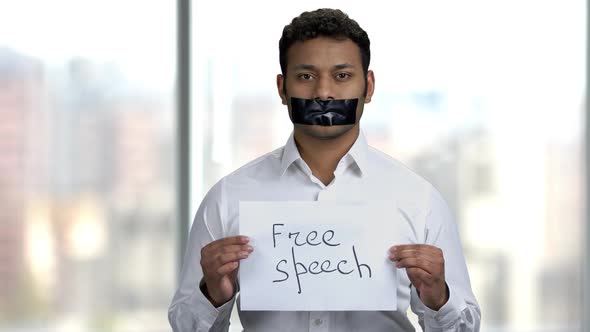 Indian Man with Taped Mouth on Blurred Background.