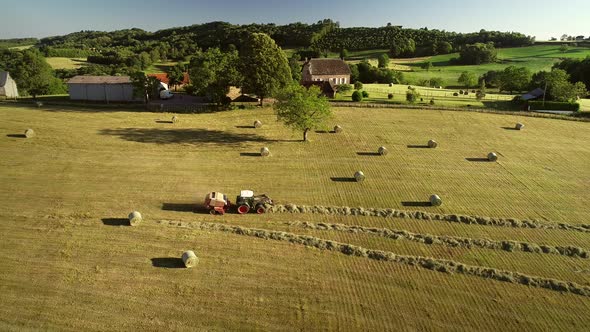 Aerial view of tractor harvesting straw bales in field, Correze, France.