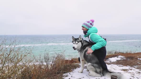 Young Beautiful Female Walking with Siberian Husky Dog on the Beach at Winter Day Slow Motion