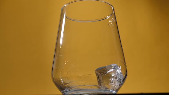 large transparent pieces of ice fall into an empty glass