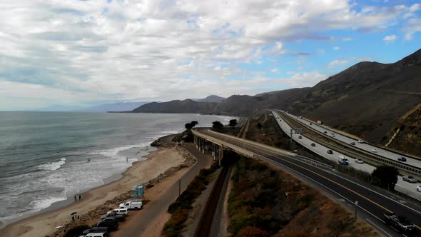 Aerial drone shot over a road bridge on the beach in Ventura next to the ocean waves and the Califor