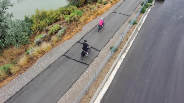 Senior couple ride on a riverside path together for exercise and bonding - aerial view