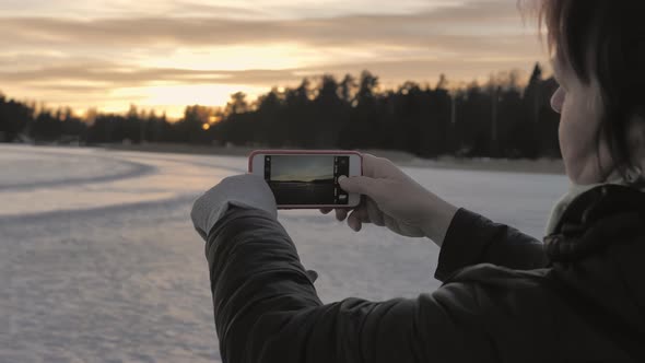 Closeup Shot of a Lady Taking a Picture of the Sunset with Her Smartphone