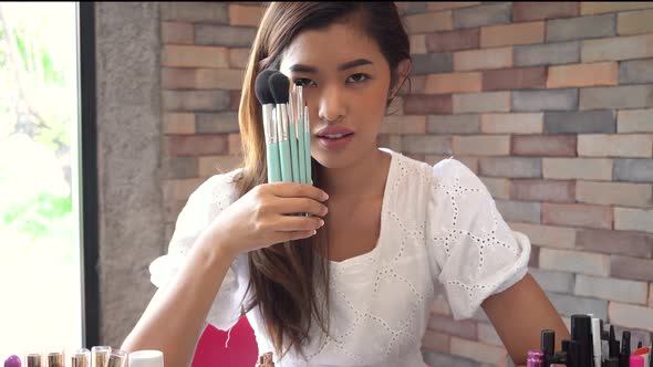 Young Positive Woman Showing Makeup Brushes