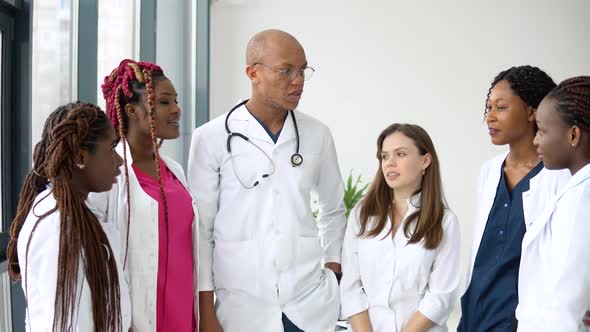 A Team of Doctors Including International Man and Women Have a Business Conversation While Standing