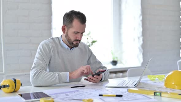 Young Architect with Documents Using Smartphone 