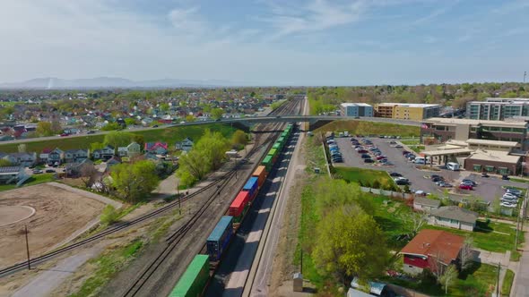 AERIAL - Train on railroad tracks under blue sky, Clearfield, Utah, forward pan left