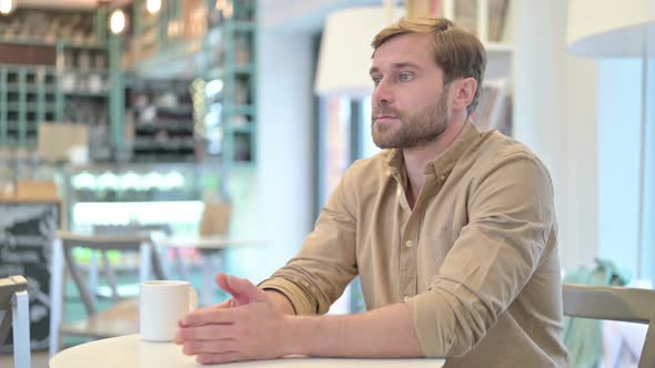 Worried Young Man Thinking of Creative Idea in Cafe