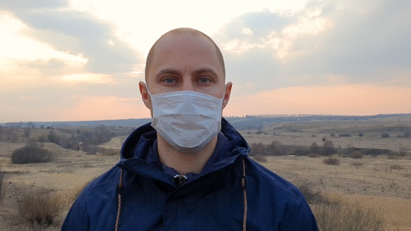 Caucasian young man with medical protective face mask looking