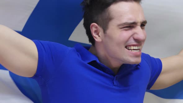 Finnish Young Man Celebrating while Holding the Flag of Finland