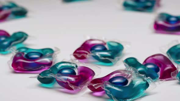 Putting Washing Gel Pod on White Table Background Closeup Capsules with Detergent for Washing