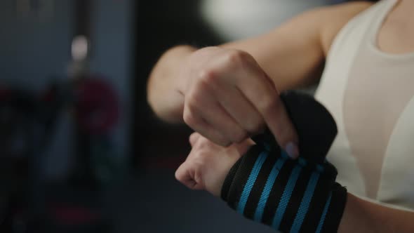 A Woman Wrapping Her Hands with Bandages Before Strength Training in the Gym