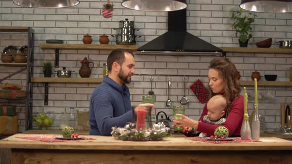 Mother, Father and a Baby Sitting at the Table in Modern Kitchen